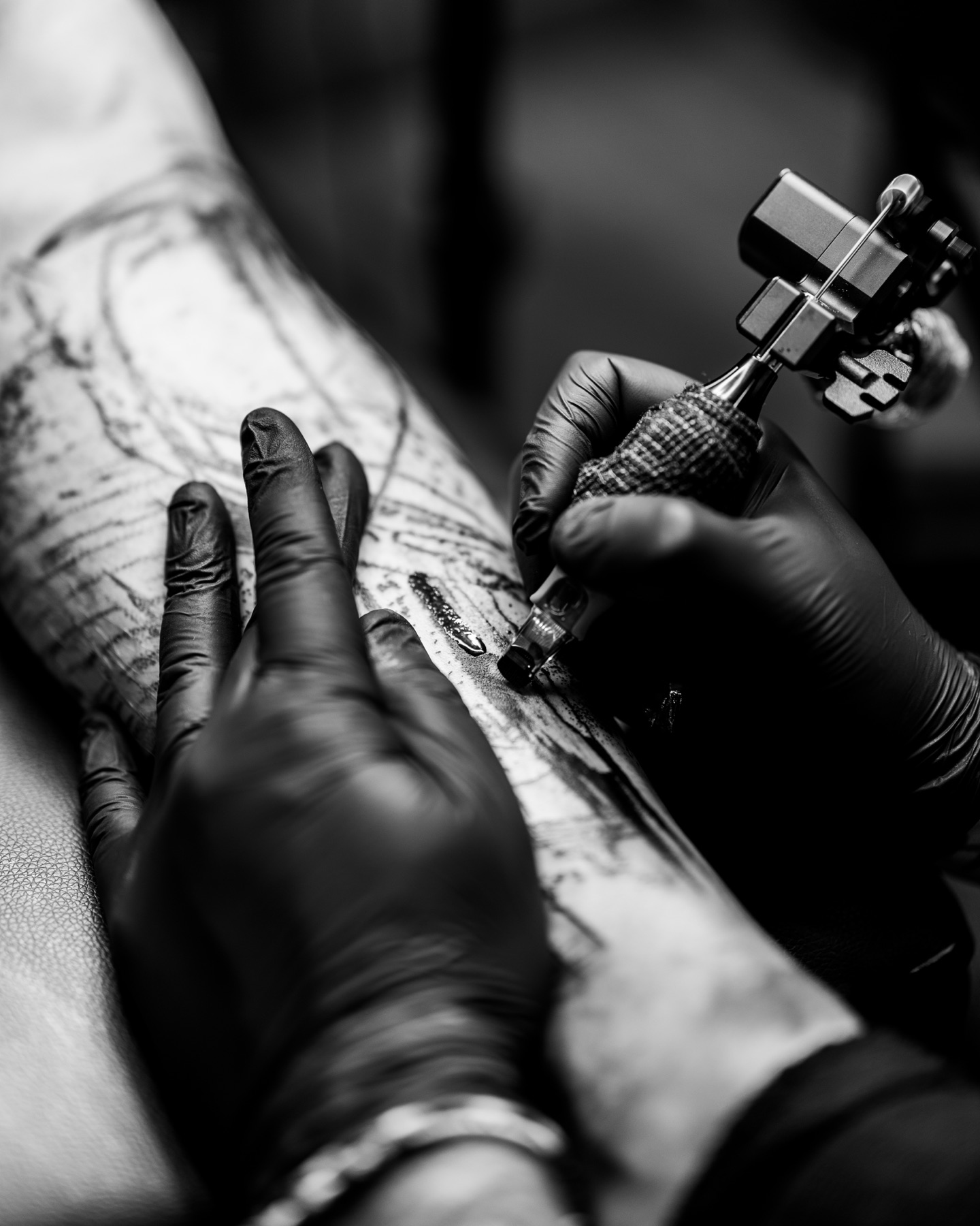 Tatoueur réalisant un motif avec des gants noirs